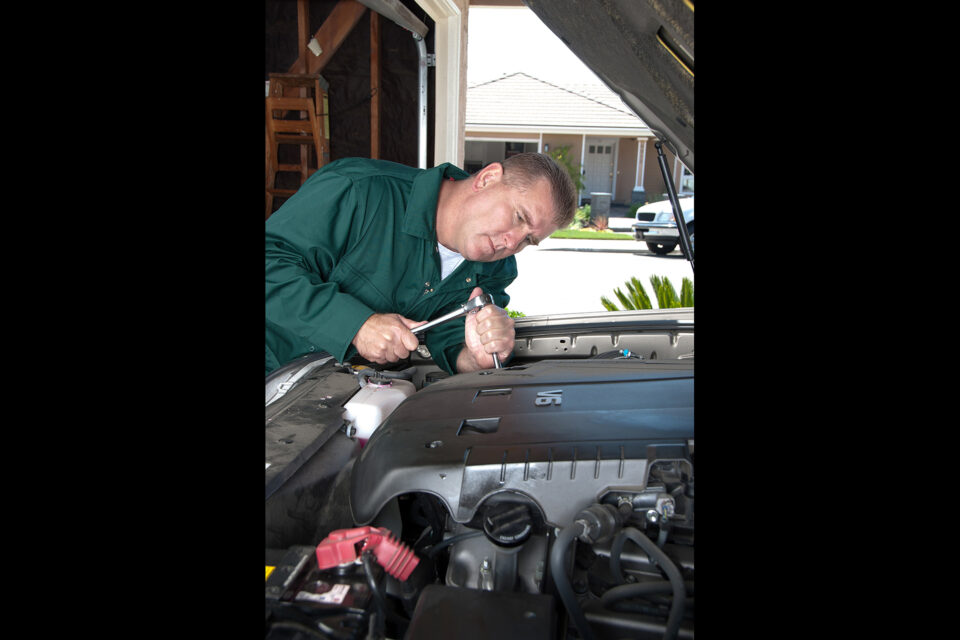 hombre utilizando un trinquete para trabajar en un motor de automóvil